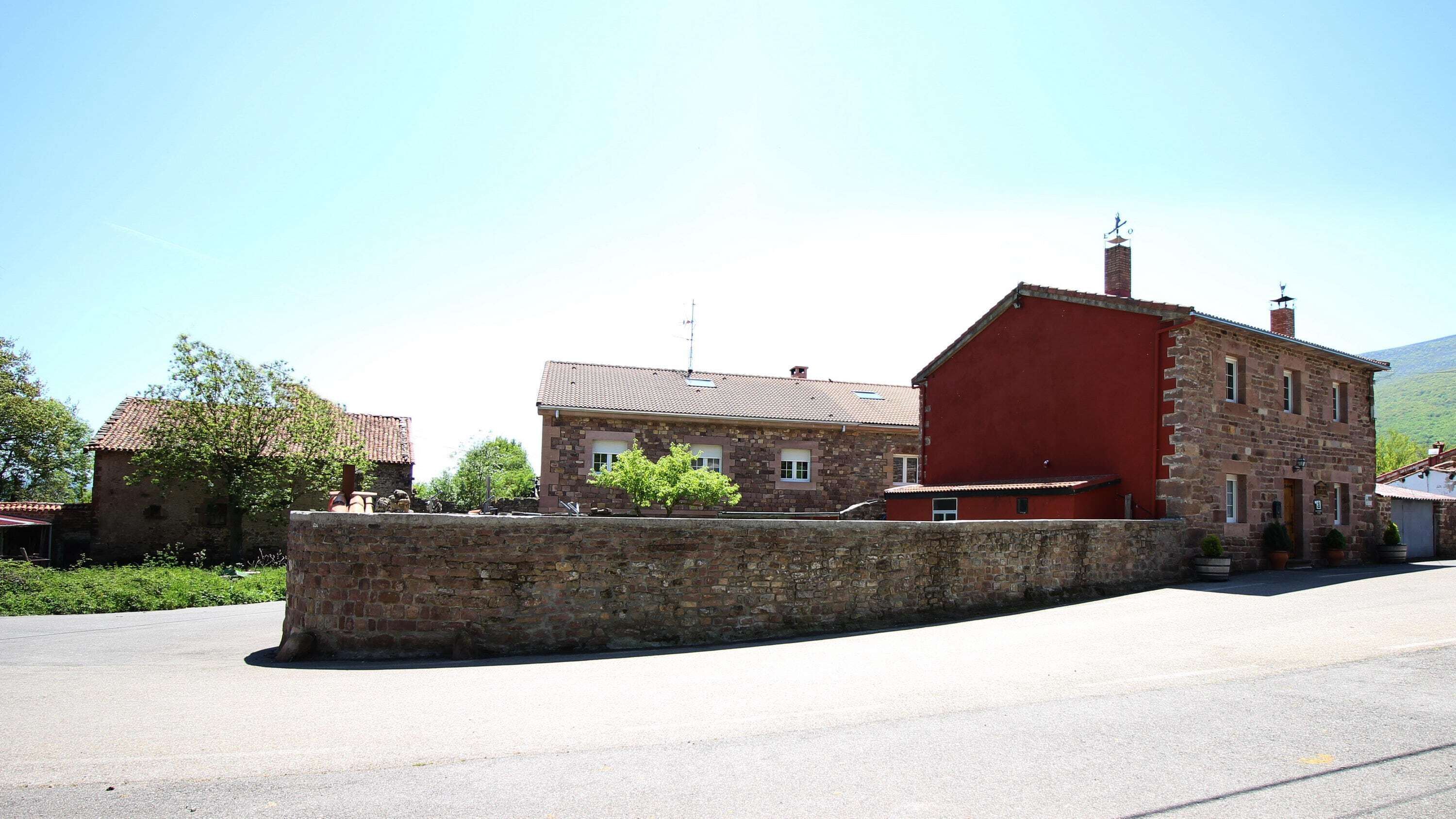 Un muro de piedra con un edificio rojo a su lado.