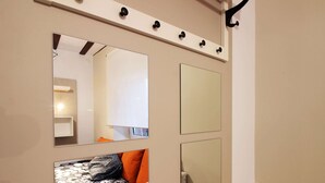 Une pièce avec un grand miroir, une petite fenêtre et une porte dotée d’une poignée noire.