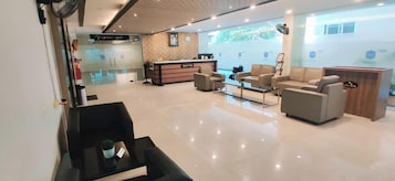 Eine moderne Hotelhalle mit einer Rezeption, einer Sitzecke und einem Konferenzsaal.