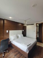 Ein Schlafzimmer mit einem großen Bett, einem Schreibtisch und einem Deckenventilator.