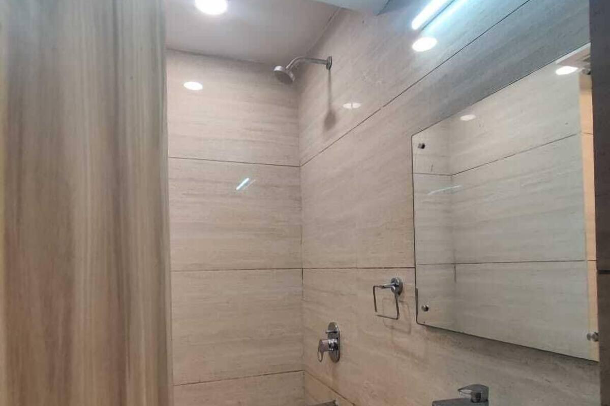 Ein modernes Badezimmer mit Holzboden, Waschbecken in Weiß und einer Dusche.