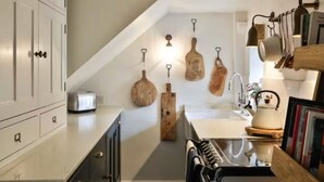 A kitchen with white cabinets, a toaster, a sink, and hanging wooden utensils.