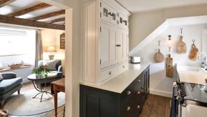 A kitchen with white cabinets, a black countertop, and a wooden ceiling.