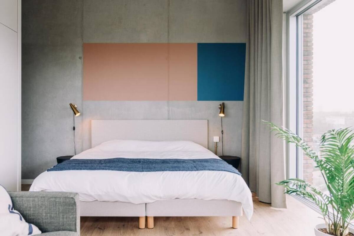 Ein modernes Schlafzimmer mit einem großen Bett, zwei Nachttischen, einer Kopfteil und einem großen Fenster mit Vorhängen.