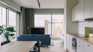 A modern apartment with a dining area, a sofa, and a kitchen.