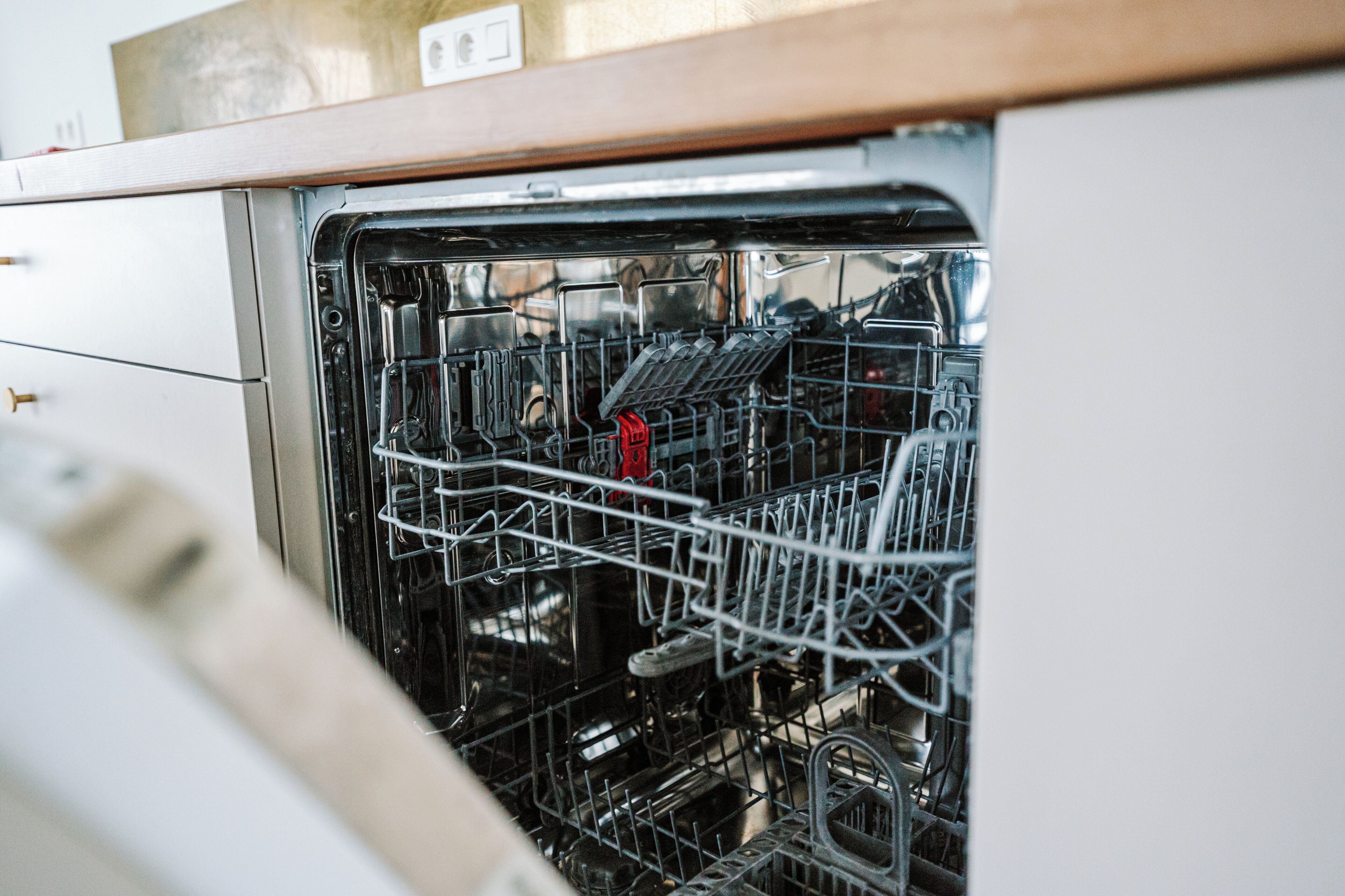 An open dishwasher with racks and utensils inside.