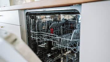 An open dishwasher with racks and utensils inside.