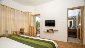 Habitación de hotel con cama, televisión, silla y balcón.