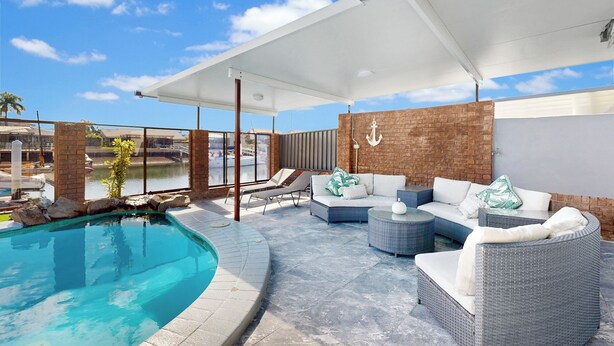 A rooftop pool area with a clear view of the marina, a white outdoor sofa set, and a brick wall with an anchor decoration. - Relfections at Newport 5Bedroom Pool and Canal Living (Newport)