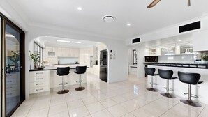 A modern kitchen with white cabinets, a black countertop, and four black bar stools. - Relfections at Newport 5Bedroom Pool and Canal Living (Newport)