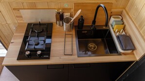 A compact kitchen with a gas stove, sink, and wooden cabinetry. - L'Échappée Royale - Tiny House 20 minutes from Beauval Zoo (Billy)