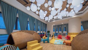 Un espace de jeux pour enfants avec des sièges confortables, des structures colorées et un design moderne au niveau du plafond.