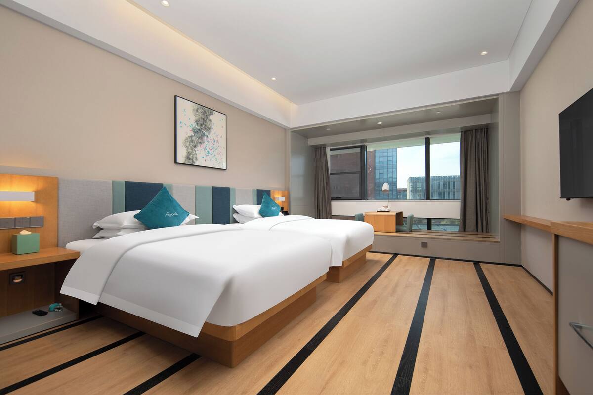 A hotel room with a large bed, bedside tables, a window with a view, and a flat-screen TV.