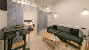 Ein modernes Wohnzimmer mit Essbereich, einer Couch und einem Couchtisch mit Flasche und Glas.