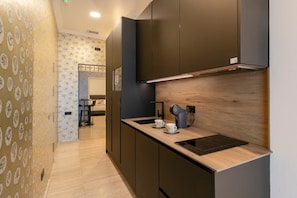 Une cuisine moderne avec des meubles de couleur sombre, un plan de travail en bois et une machine à café.