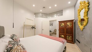 Ein Schlafzimmer mit einem Bett, einem Kleiderschrank, einem Spiegel und einer Tür zu einem anderen Raum.