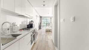 Een moderne keuken met witte kasten, roestvrijstalen apparatuur en een houten vloer.