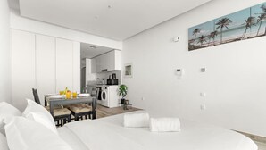Een moderne hotelkamer met een groot bed, een eethoek en een keuken.