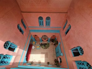 An interior courtyard with a tiled floor, a central seating area, and blue-framed windows. - Riad Massin Marrakech (Marrakech)