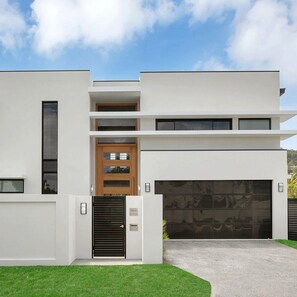 A modern two-story house with a garage, a front door, and a small window on the left side.