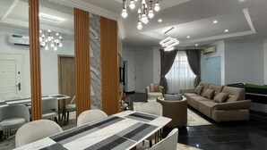 Ein modernes Wohnzimmer mit Essbereich, ausgestattet mit einem großen Tisch, Sofas und einem Billardtisch.
