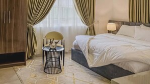 Ein Hotelzimmer mit Bett, Stuhl, kleinem Tisch und Vorhängen.