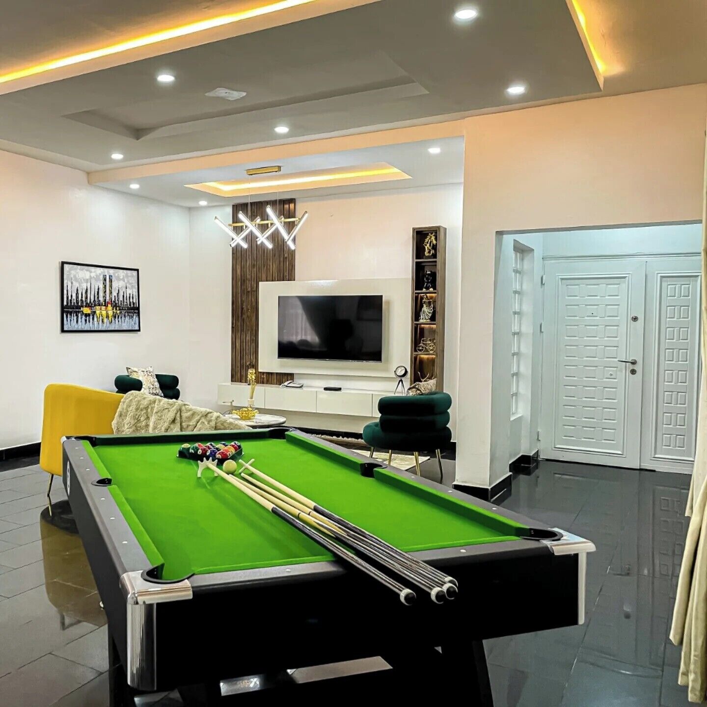 A modern living room with a pool table, a television, and a decorative shelf.