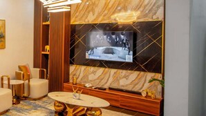 Ein modernes Wohnzimmer mit einem großen Flachbildfernseher an einer Marmorwand, einem eleganten Couchtisch und zeitgemäßen Möbeln.