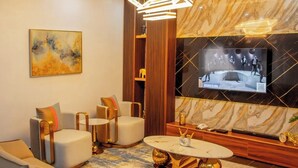 Ein modernes Wohnzimmer mit großem Flachbildfernseher, bequemen Sitzgelegenheiten und einem einzigartigen Couchtisch.
