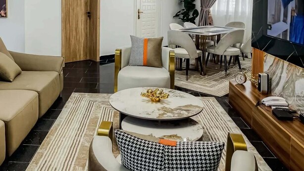 Ein modernes Wohnzimmer mit Sofa, Couchtisch, Fernseher und Essbereich.