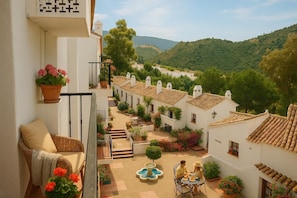 A courtyard with a dining table, potted plants, and a fountain.