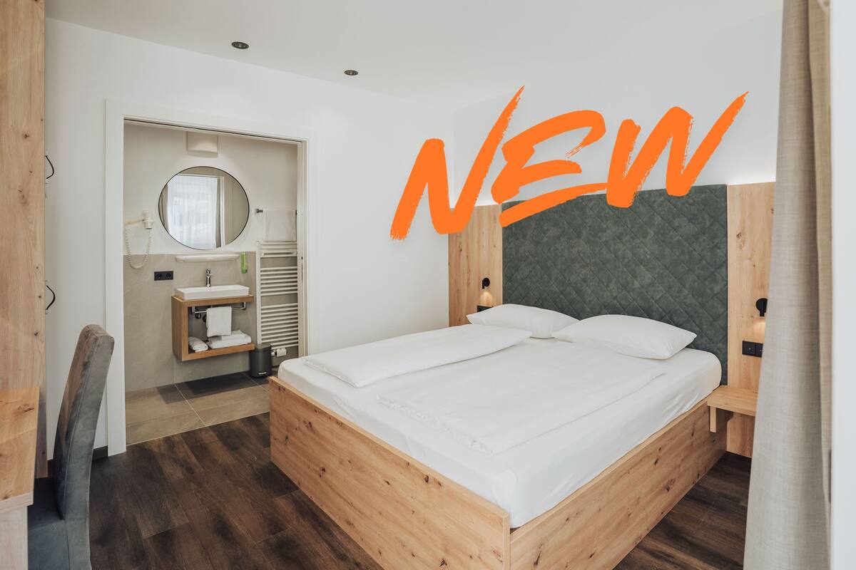 Une chambre moderne avec un lit en bois, un lavabo intégré et un miroir rond.