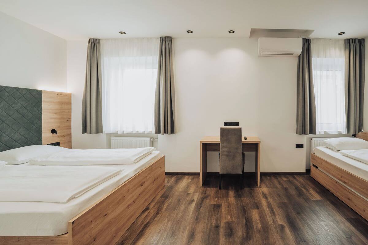 Une chambre d’hôtel avec deux lits en bois, un bureau et une chaise.