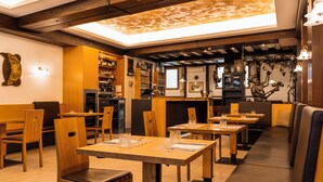 Ein Restaurant mit Holztischen und -stühlen, einer Bar und einer Sitzgelegenheit mit gepolsterten Bänken.