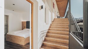 Ein Schlafzimmer mit einem hölzernen Bett, einer Treppe zu einem Außenbereich und Blick auf die Stadt.
