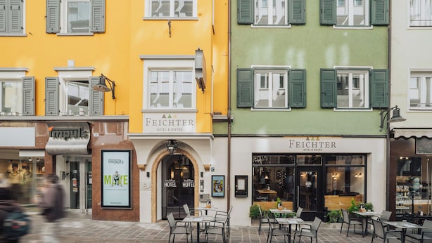 Ein Hotel mit gelber Fassade und grünen Fensterläden, inklusive Außenbereich zum Sitzen und einem gut sichtbaren Eingang.