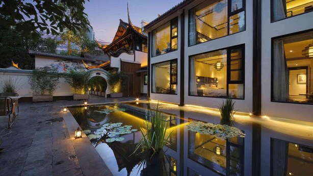 A modern building with large windows, a courtyard with a reflective water feature, and traditional architectural elements. - Chengdu Qingyang Palatio Huajian Mansion (Chengdu)