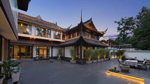 A traditional building with a courtyard, modern glass doors, and potted plants. - Chengdu Qingyang Palatio Huajian Mansion (Chengdu)