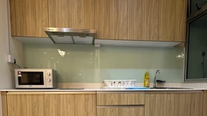 Et moderne køkken med træskabe, et rustfrit stål emfang, en mikrobølgeovn og en vask.