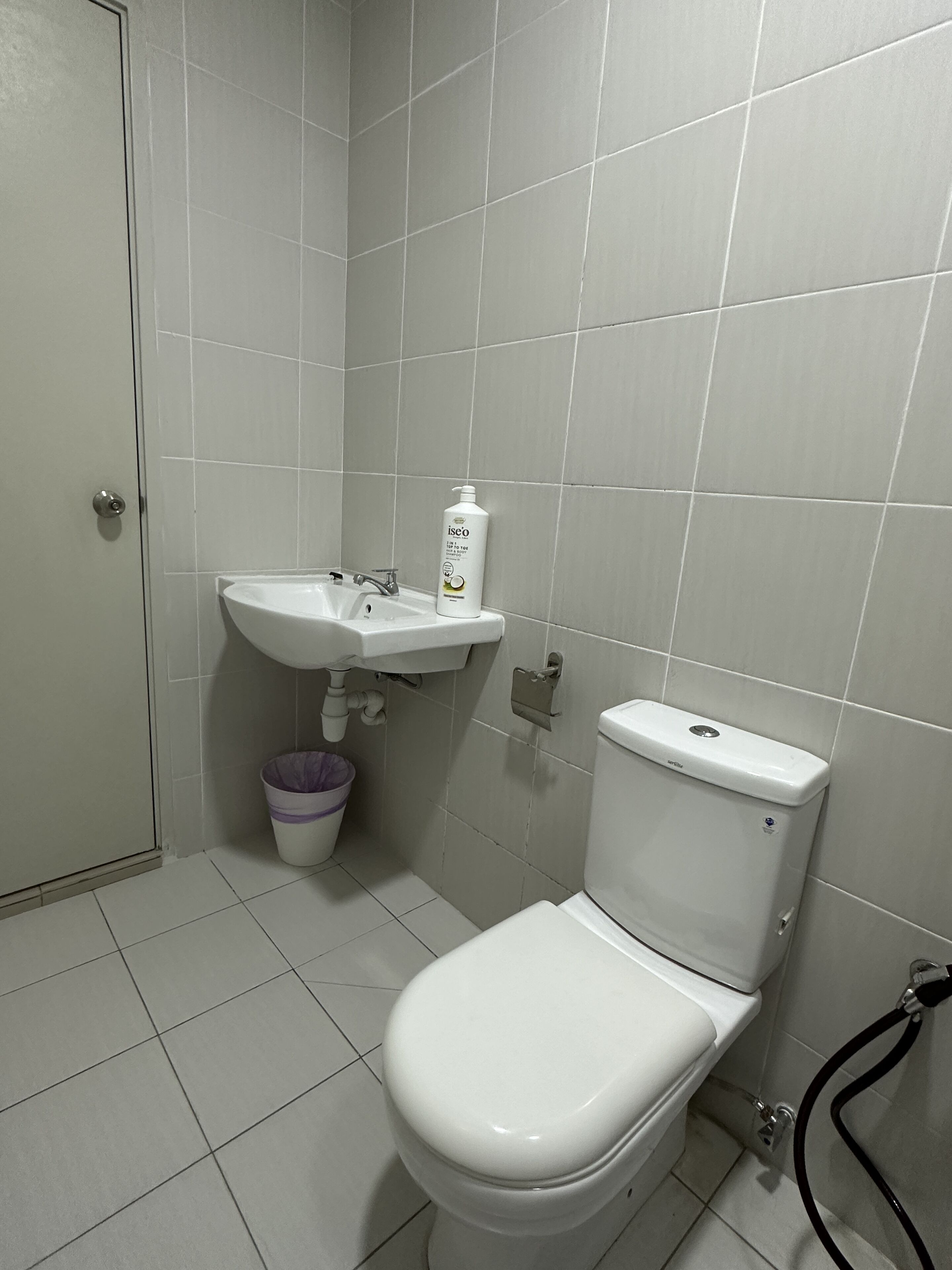 A small, clean bathroom with a toilet, sink, and a trash bin.