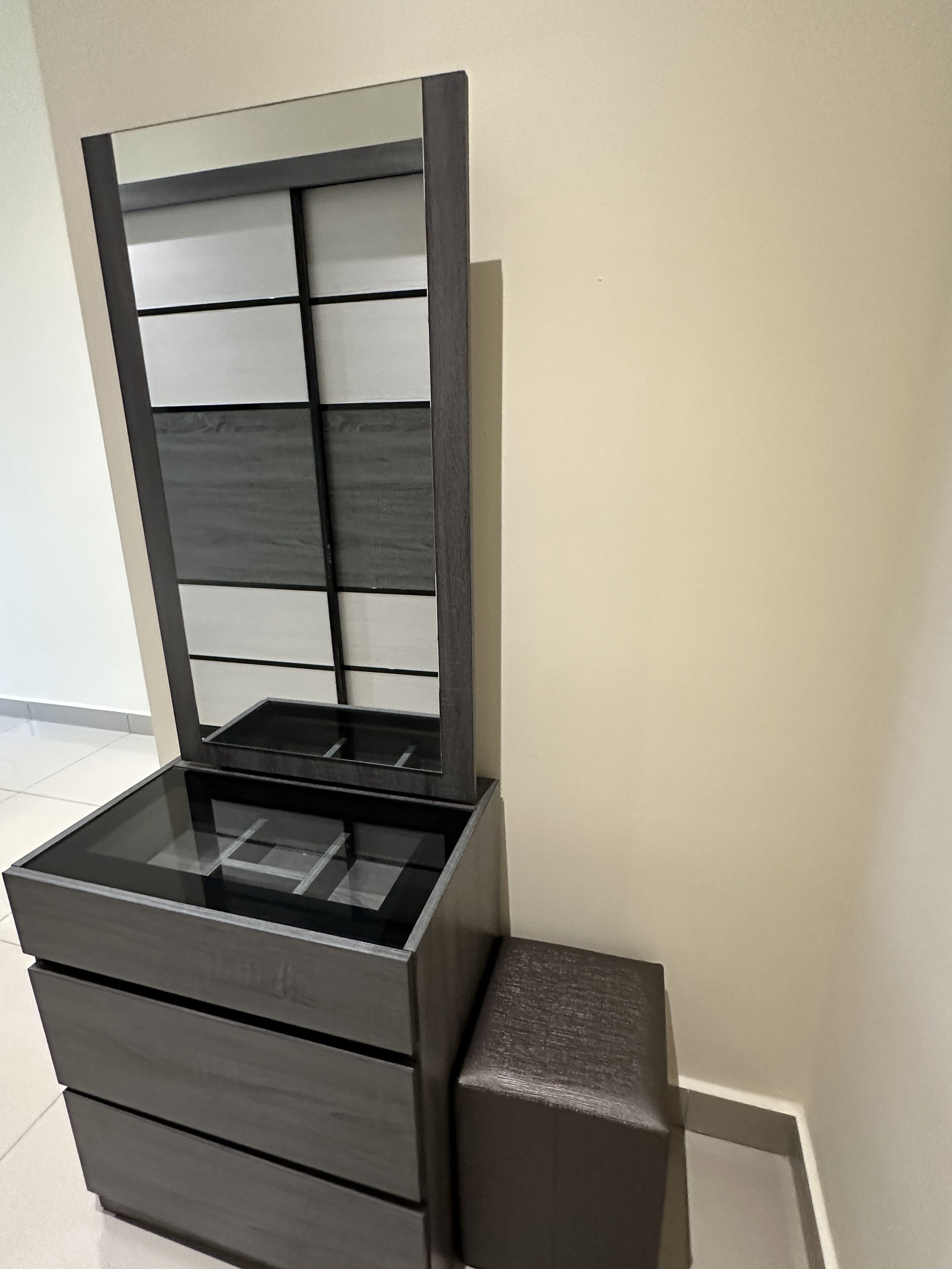 A modern, minimalist dresser with a glass top and multiple drawers.
