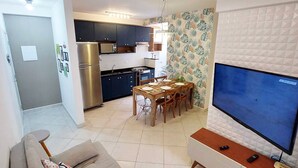 A compact living space with a kitchenette, dining area, and a TV. - Complete apartment in Ubatuba - Itaguá with air conditioning + Wifi (Itaguá Ubatuba)