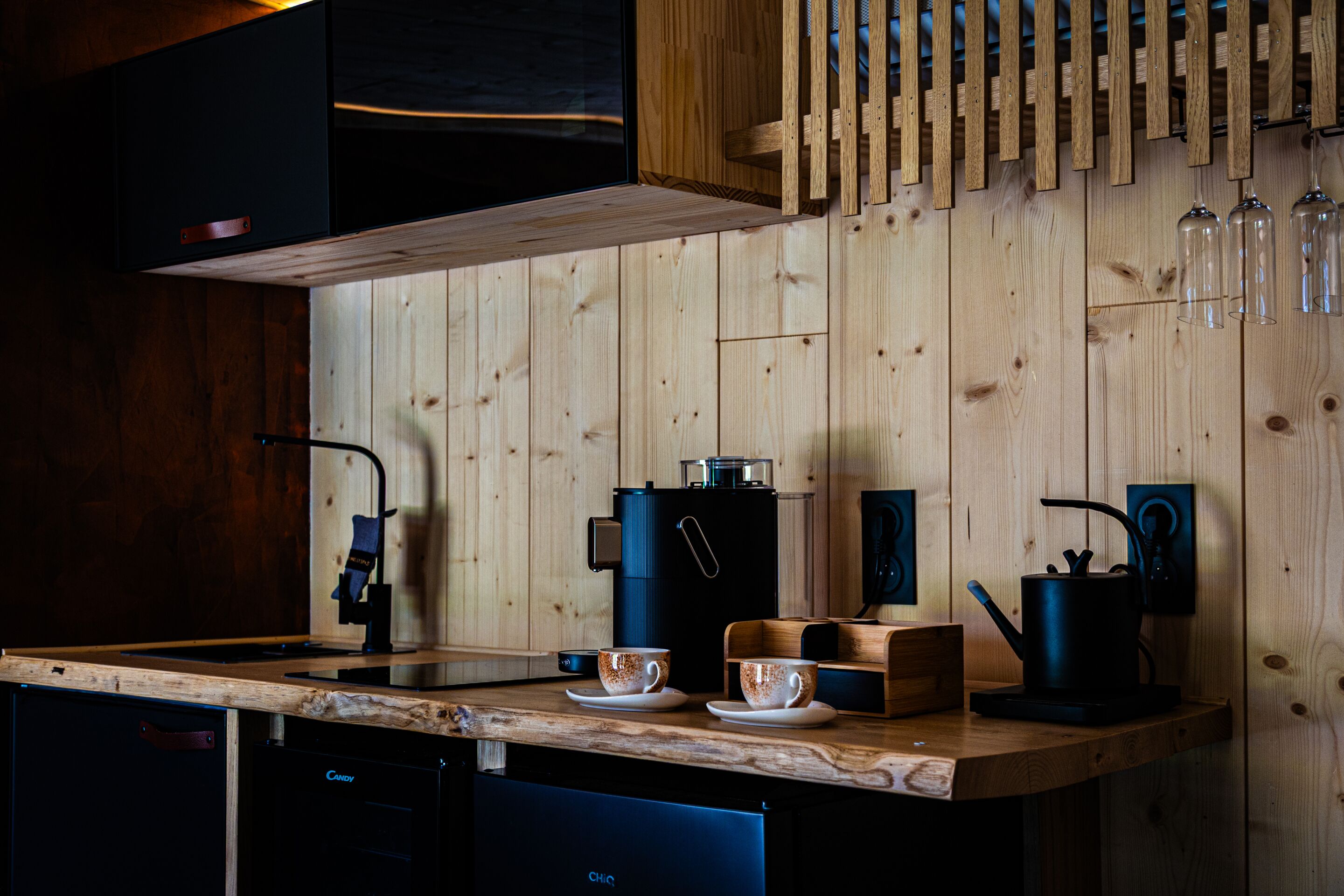 A modern kitchen with wooden cabinetry, a coffee machine, a kettle, and a sink.