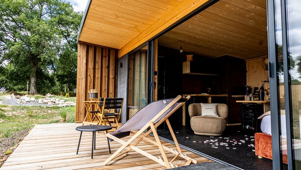 A wooden deck with a folding chair, a small table, and a sofa. - Pépites Lodges et Spas (Prémilhat)