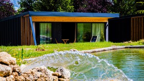 A modern outdoor pool area with a wooden deck and a glass enclosure. - Pépites Lodges et Spas (Prémilhat)
