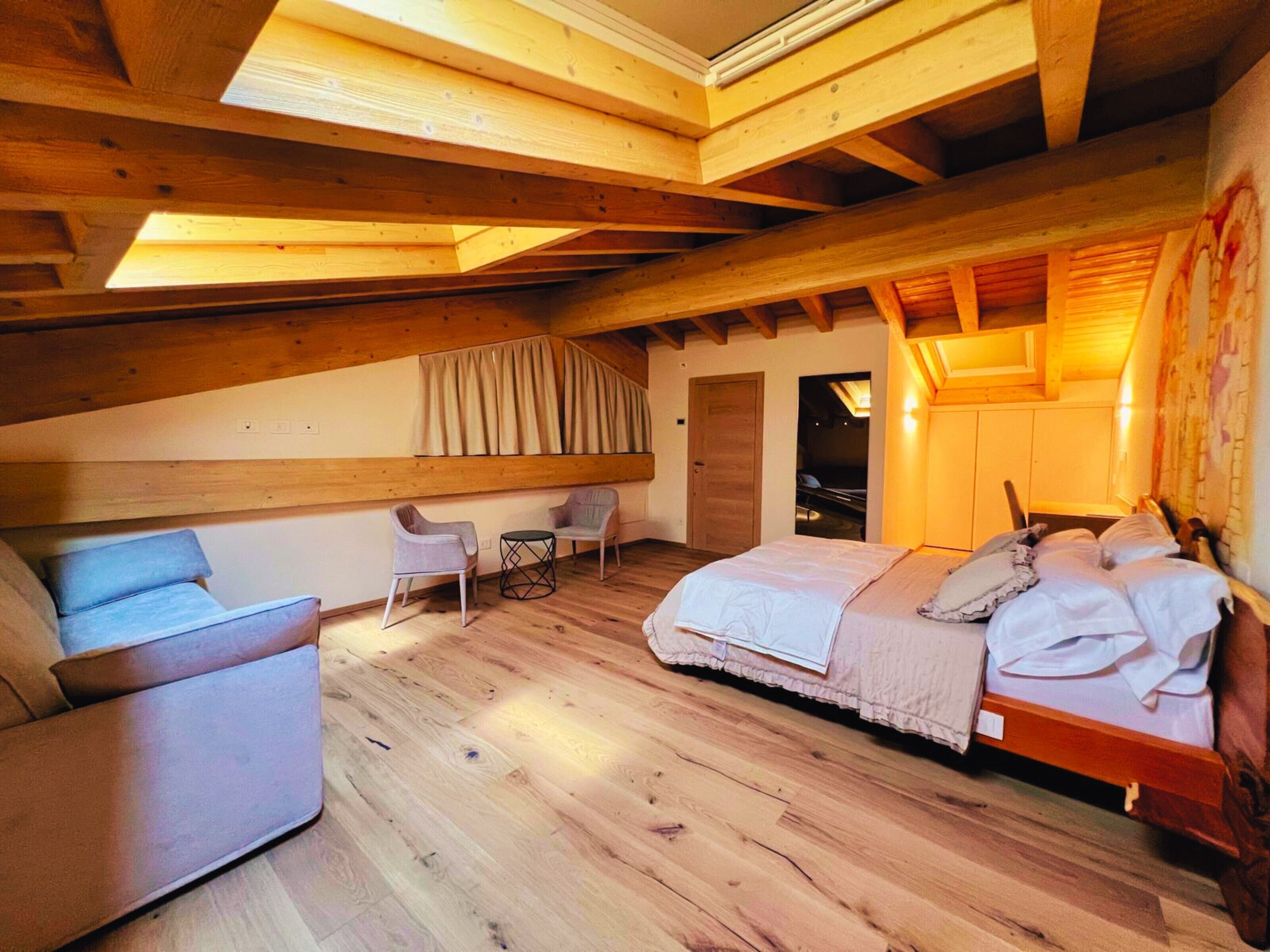 Ein gemütliches Schlafzimmer mit Holzboden, einem Bett, einem Sessel und einem kleinen Tisch.