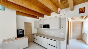 A compact kitchen with white cabinets, a microwave, and a small refrigerator. - 45 m² Room with Private Bathroom – Up to 2 Guests (Illasi)