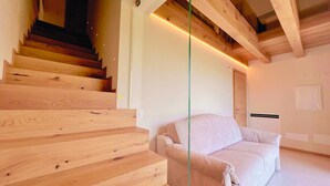 A modern interior with a wooden staircase, a sofa, and a ceiling with exposed beams. - 45 m² Soundproof Room with Private Bathroom and Terrace – Up to 4 Guests (Illasi)