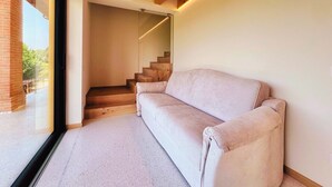 A modern interior with a wooden staircase, a beige sofa, and a glass door leading outside. - 45 m² Soundproof Room with Private Bathroom and Terrace – Up to 4 Guests (Illasi)