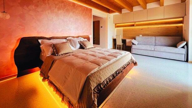 A modern bedroom with a wooden ceiling, a large bed, a sofa, and built-in lighting. - 45 m² Soundproof Room with Private Bathroom and Terrace – Up to 4 Guests (Illasi)